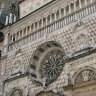 Bergame - Cappella Colleoni,  détail de la façade : statues des vertus surmontant les pilastres des fenêtres qui encadrent le portail. De chaque côté de la rosace, les médaillons représentent Jules César et Trajan. En partie supérieure, une loggia de style roman.